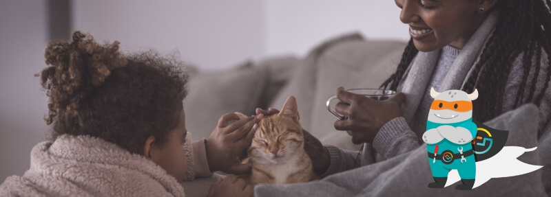 A woman and child sitting on a couch petting a cat