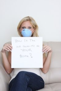 woman-wearing-mask-and-holding-sign-that-says-how-is-the-air-quality-in-your-home